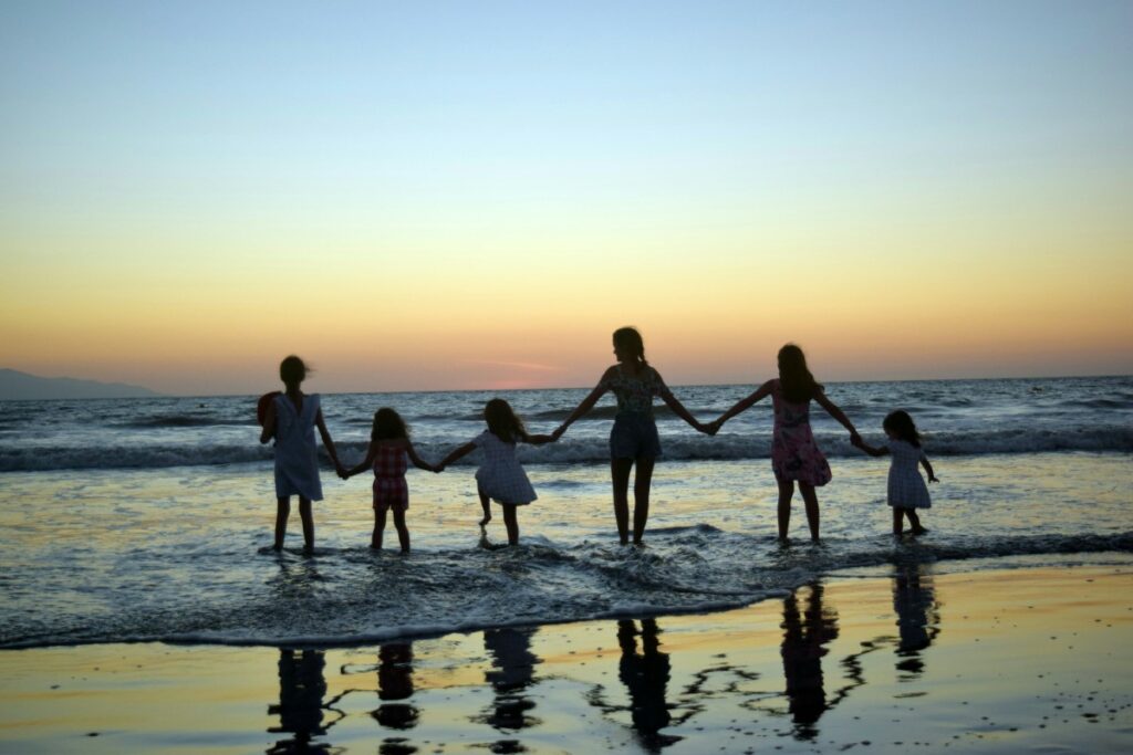 Niñas de familia numerosa durante viaje entran al mar en el atardecer